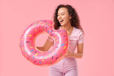 Pembe arka planda şişirilebilir yüzüğü olan güzel bir Afro-Amerikalı kadın.