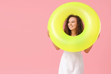 Pembe arka planda şişirilebilir yüzüğü olan güzel bir Afro-Amerikalı kadın.