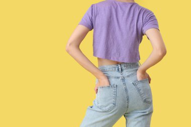 Sarı arka planda şık kotlu güzel bir kadın.