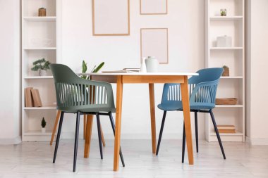 Odada sandalyeli, raflı ve çerçeveli bir masa.