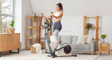 Sportif genç Afro-Amerikalı kadın oturma odasında makine eğitimi alıyor.