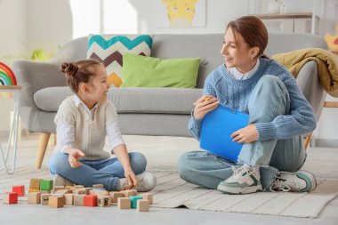 Kadın psikolog ofiste küçük bir kızla konuşuyor.