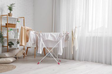 Çamaşırhanenin içinde kurutucuda temiz giysiler asılı.