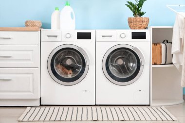 Çamaşır makineleri ve deterjan şişeleriyle modern çamaşır odasının içinde.