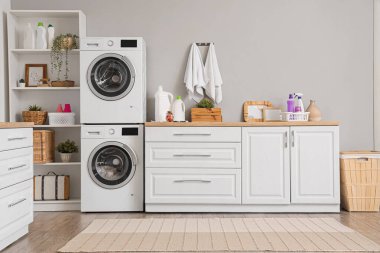 Çamaşır makineleri ve temizlik malzemeleriyle modern çamaşır odasının içinde.