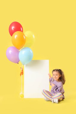 Balonları ve sarı arka planda boş kartı olan tatlı küçük bir kız.
