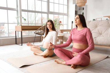 Hamile bayan arkadaşlar evde meditasyon yapıyorlar.