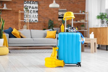 Oturma odasında şapka, güneş kremi ve şnorkelle yüzme malzemeleriyle dolu bir bavul. Seyahat kavramı