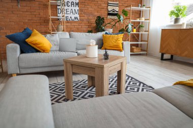 Gri kanepeleri, laptopu ve ahşap sehpası olan modern oturma odasının içinde.