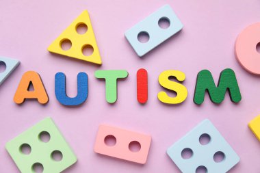 Kelime AUTISM ve Leylak arka planında eğitici oyuncaklar. Üst görünüm