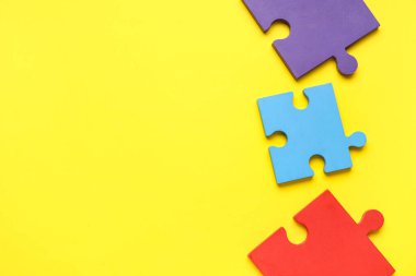 Sarı arka planda renkli yapboz parçaları. Otistik bozukluk kavramı. Üst görünüm