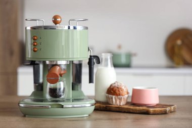 Modern kahve makinesi. Mutfaktaki masada bir fincan sıcak espresso ve kek.