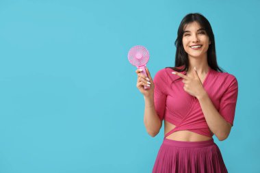 Mavi arka planda mini fanı olan genç bir kadın.