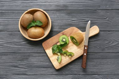 Siyah ahşap arka planda taze kivi ile kase ve yemek.