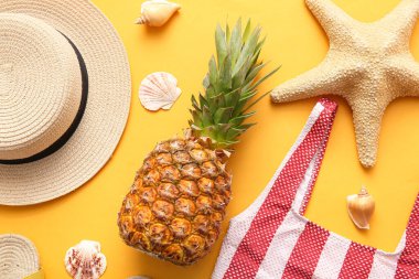 Hasır şapkalı, mayolu, deniz yıldızlı ve turuncu kaplamalı taze ananas.