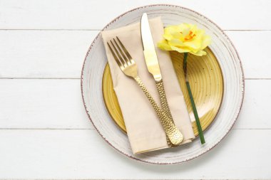 Altın çatal bıçaklı şık masa ve beyaz ahşap arka planda güzel bir çiçek.