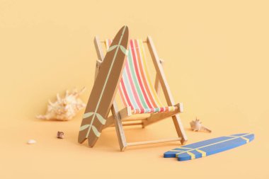 Güverte sandalyesi, sörf tahtaları ve sarı arka planda deniz kabukları. Yaz konsepti