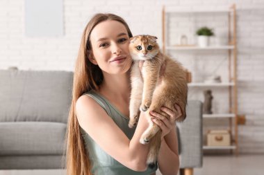 Evde yoga minderinde oturan sevimli kedisi olan genç bir kadın.