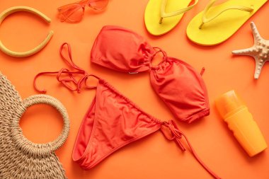 Şık kadın mayoları, plaj aksesuarları ve arka planda güneş kremi olan kompozisyon