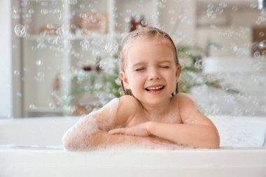 Sabun köpüklü şirin küçük kız banyoda banyo yapıyor.