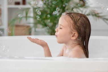 Sabun köpüklü şirin küçük kız banyoda banyo yapıyor.