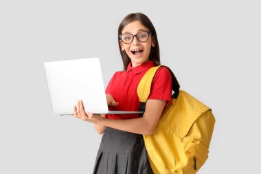 Gözlüklü küçük kız, arka planda dizüstü bilgisayar kullanıyor.