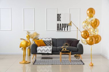 Evdeki beyaz duvarın yanında kanepeli ve altın rengi flamingolu güzel hava balonları.