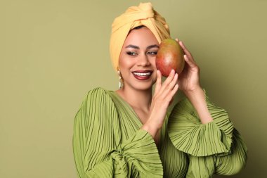Yeşil arka planda taze mangolu güzel bir Afro-Amerikalı kadın.
