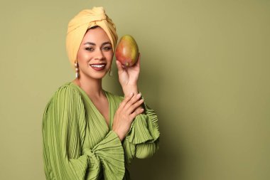 Yeşil arka planda taze mangolu güzel bir Afro-Amerikalı kadın.