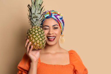 Bej arka planda taze ananaslı güzel bir Afro-Amerikalı kadın.