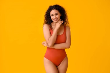 Sarı arka planda şık kırmızı mayo giyen güzel Afro-Amerikalı kadın.