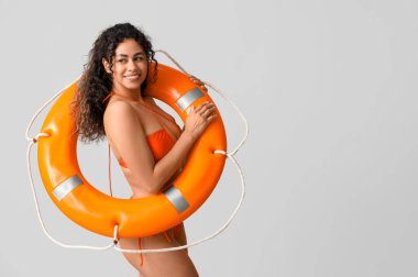 Gri arka planda can simidi olan şık turuncu mayolu güzel Afro-Amerikalı kadın.