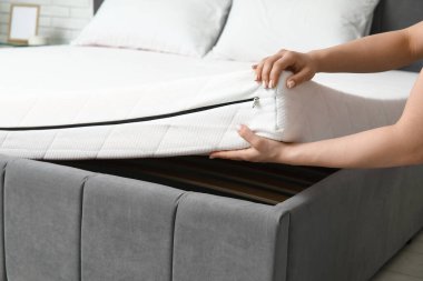 Kadın evdeki yatağa yumuşak ortopedik yatak koyuyor, yakın plan.