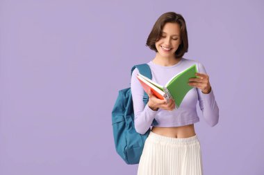 Sırt çantası ve eflatun üzerine not defterleri olan güzel bir kız öğrenci.