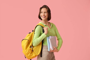 Pembe arka planda kitapları ve sırt çantası olan güzel bir kız öğrenci.