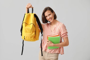 Gri arkaplan üzerine not defterleri ve sırt çantasıyla güzel bir kız öğrenci.