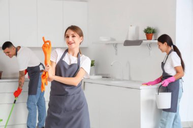 Kadın hademe mutfakta lastik eldiven takıyor.