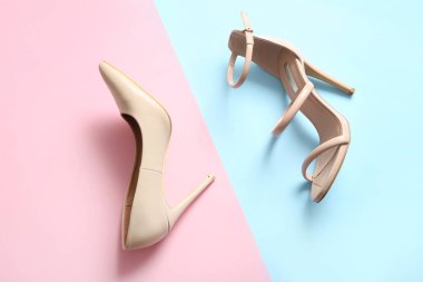 Different high-heeled shoes on color background