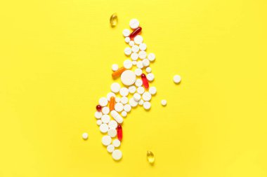 Sarı arka planda farklı haplar içeren kompozisyon