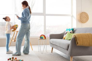 Ofiste resim yapan küçük bir kızla çalışan kadın psikolog.