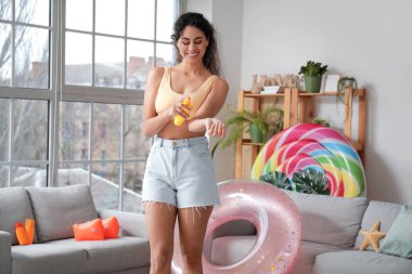 Afro-Amerikalı genç bir kadın oturma odasında sprey kullanıyor.