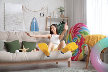 Oturma odasındaki kanepede yüzgeçli genç ve güzel bir kadın yatıyor.