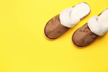 Sarı arka planda bir çift kahverengi yumuşak terlik. Üst görünüm