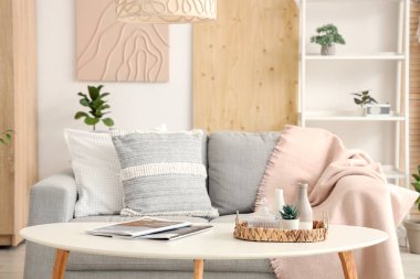 Şık oturma odasının içinde kanepe, yastık, raf ünitesi ve kahve masası var.