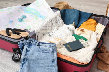 Kadın kıyafetleri, harita ve pasaport dolu bavulu aç. Seyahat kavramı