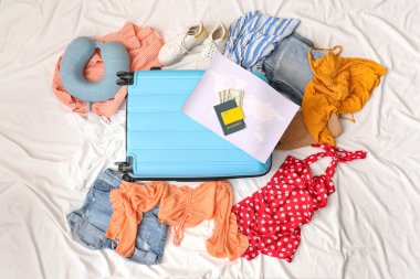 İçinde eşyalar ve pasaport olan bavullar beyaz arka planda. Seyahat kavramı