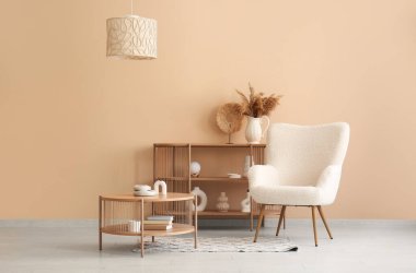 Sıcak koltuk, raf ünitesi ve bej duvarın yanındaki sehpa.