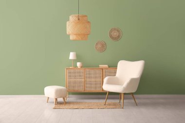 Yeşil duvarın yanında içi puf ve göğüs dolu beyaz koltuk.