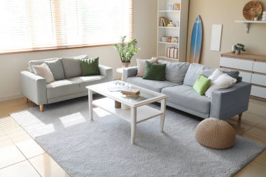 Oturma odasında rahat bir kanepe, masa ve sörf tahtası var.