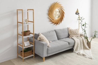 Şık oturma odasının içinde rahat bir kanepe, ekose ve minderler, lamba ve ayna var.